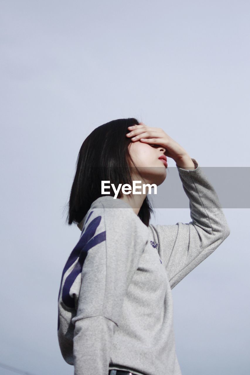 Young woman standing against clear sky