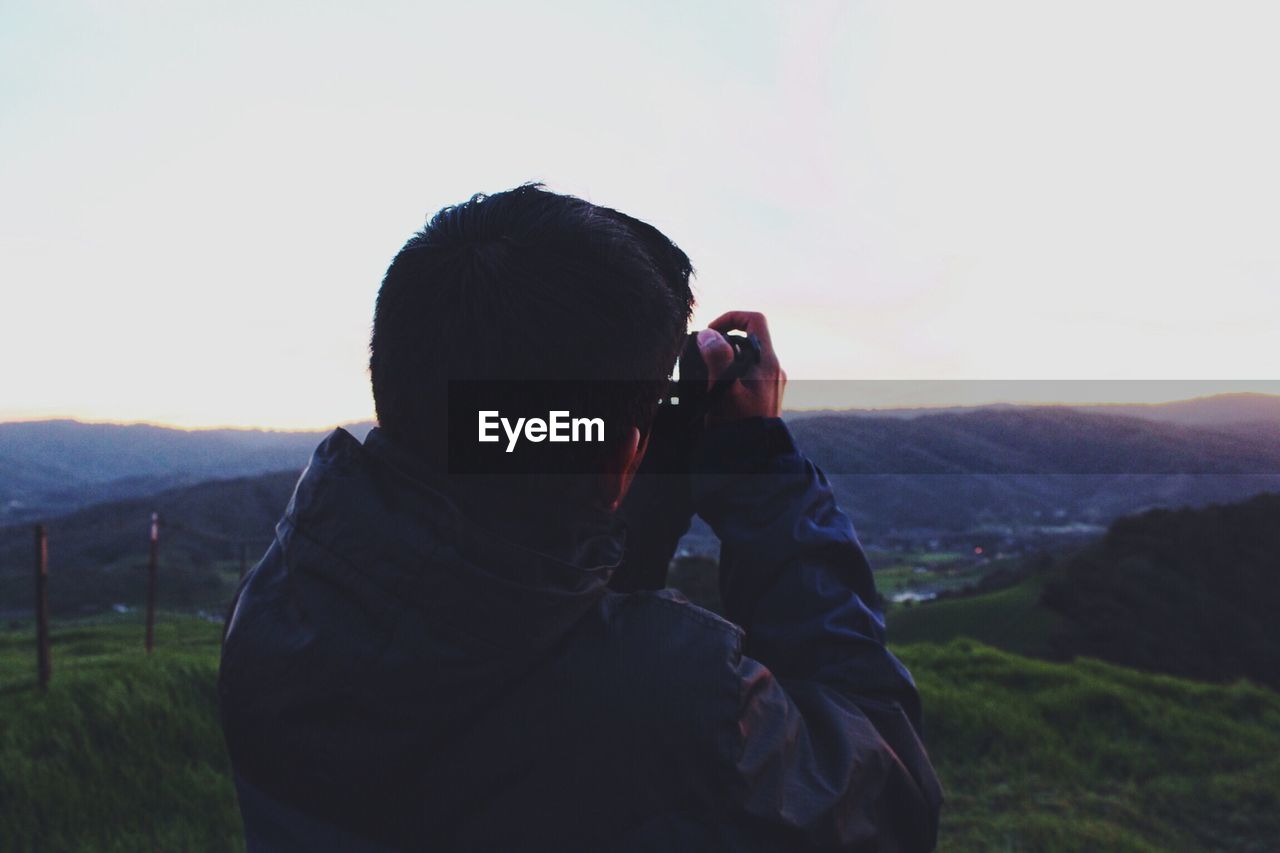 WOMAN PHOTOGRAPHING THROUGH MOUNTAIN LANDSCAPE