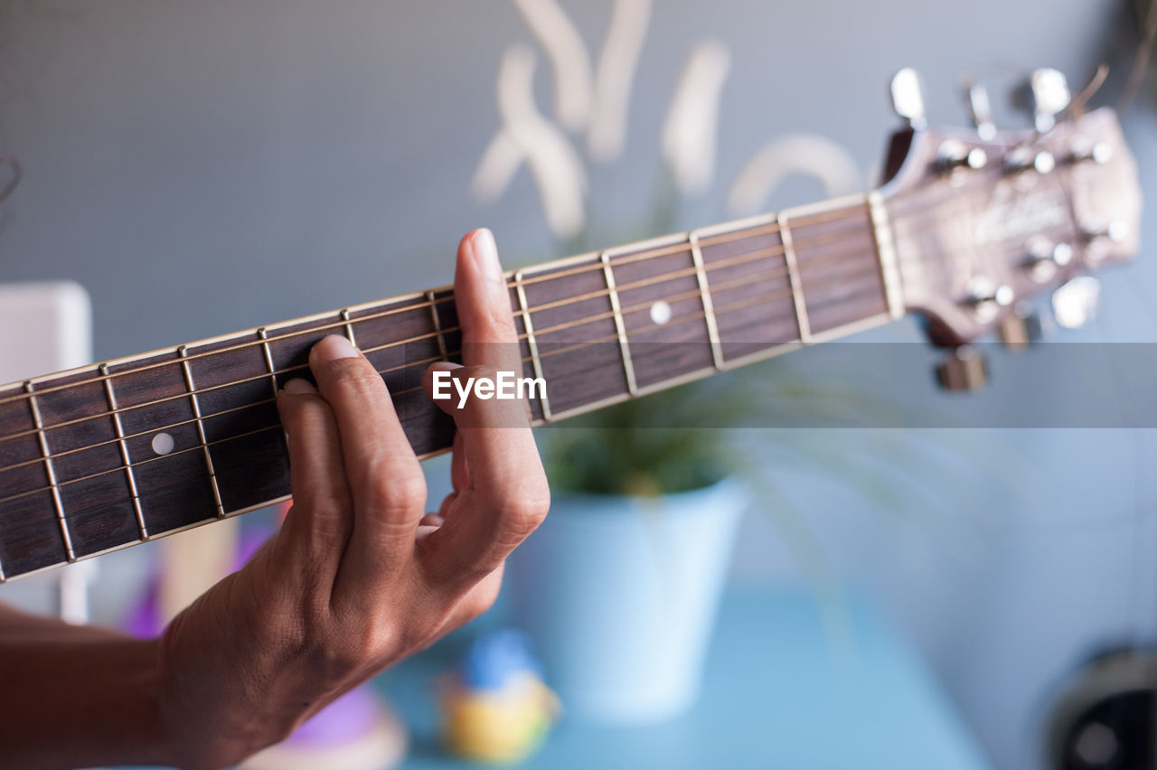 Cropped hand playing guitar at home