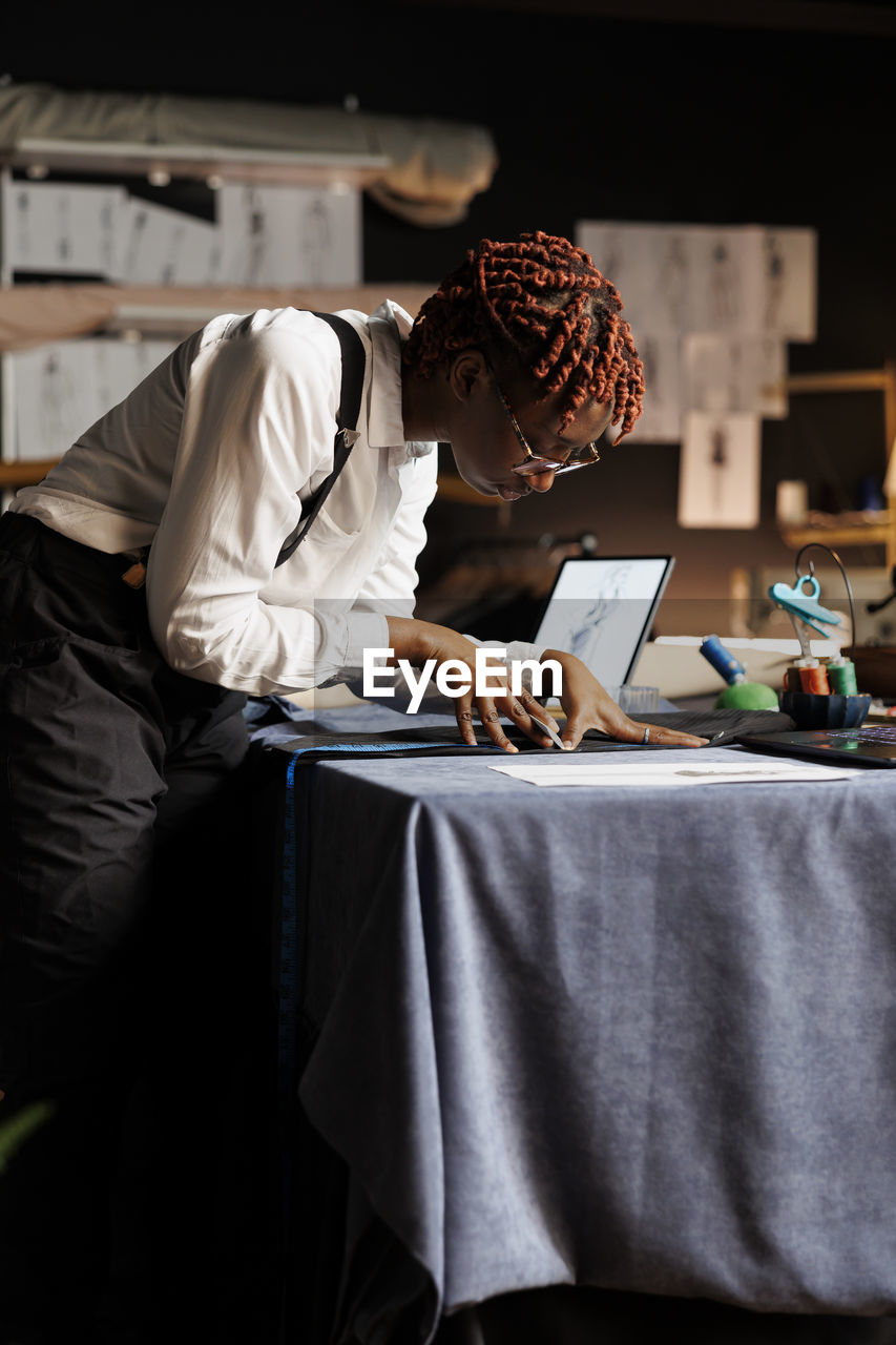 side view of woman using laptop while sitting on table