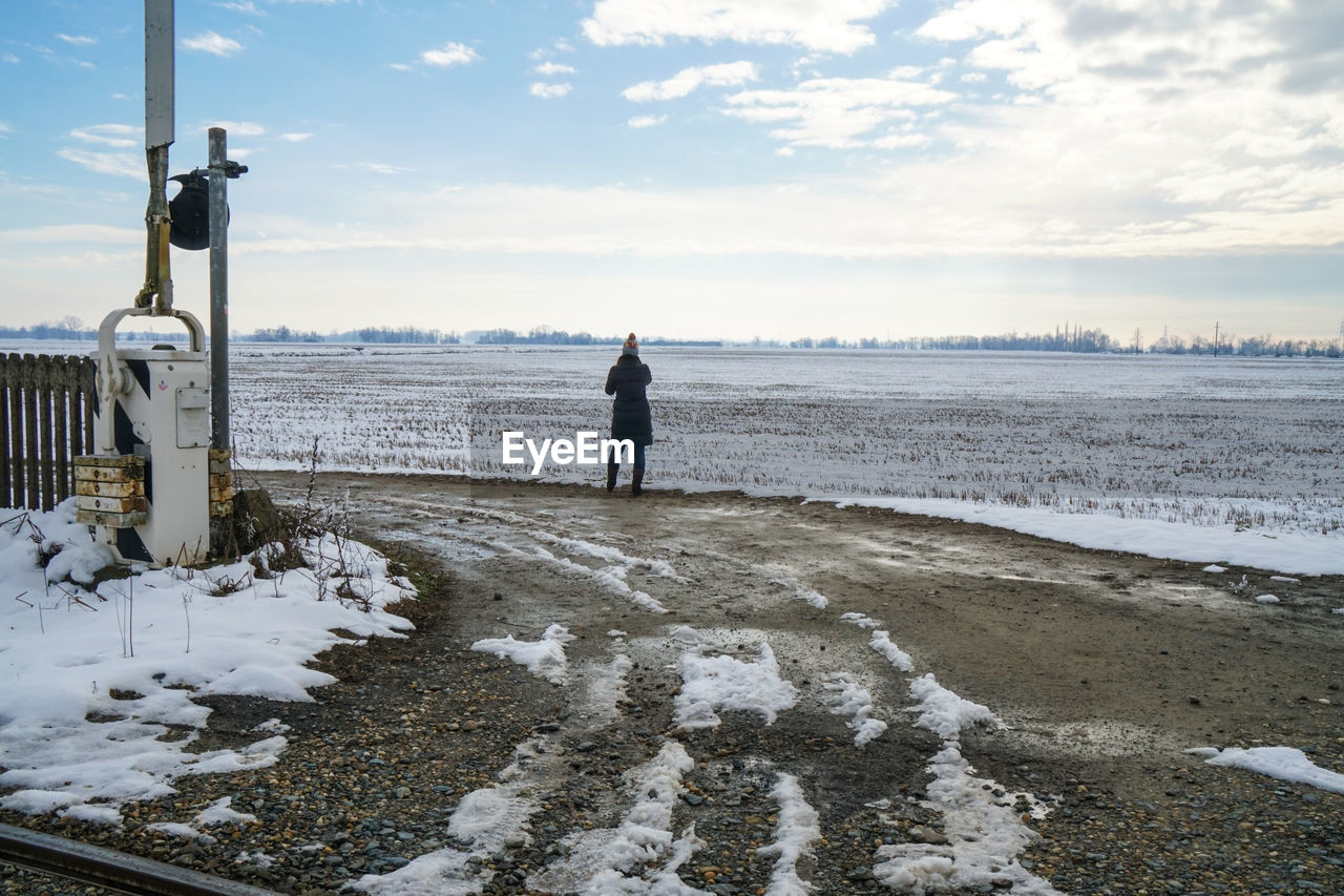 Rear view of woman standing at beach during winter