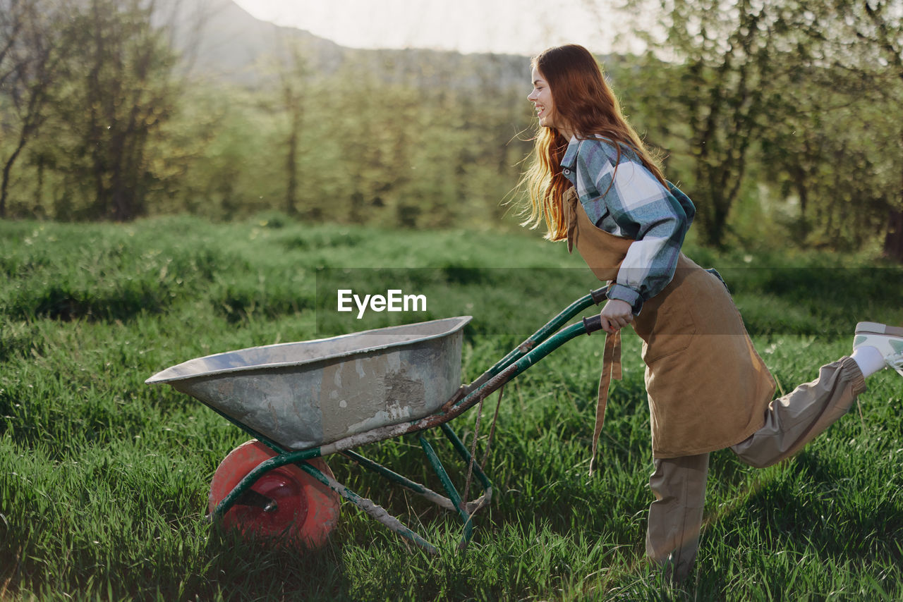 Playful woman with wheelbarrow in field