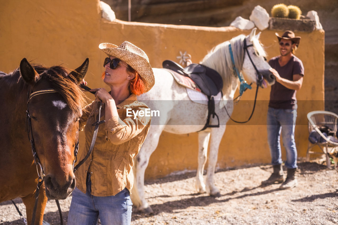 Friends preparing horses for riding