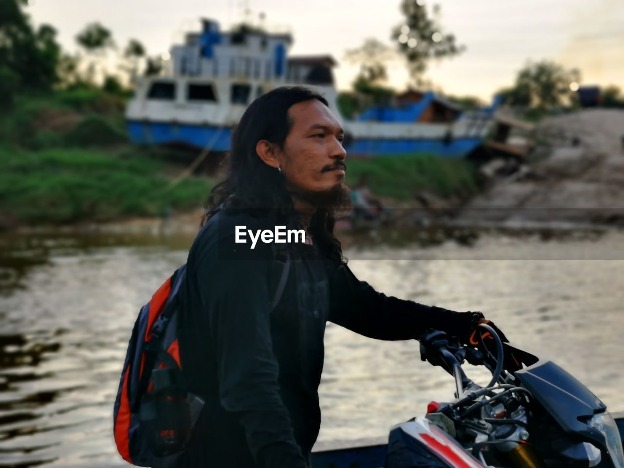 Portrait of asian man with long hair on river background