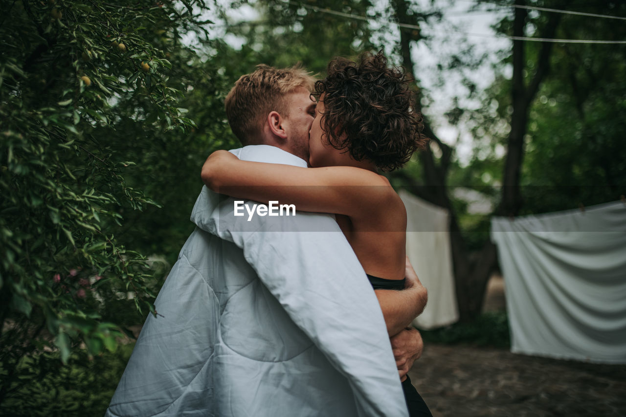 Rear view of couple kissing against trees