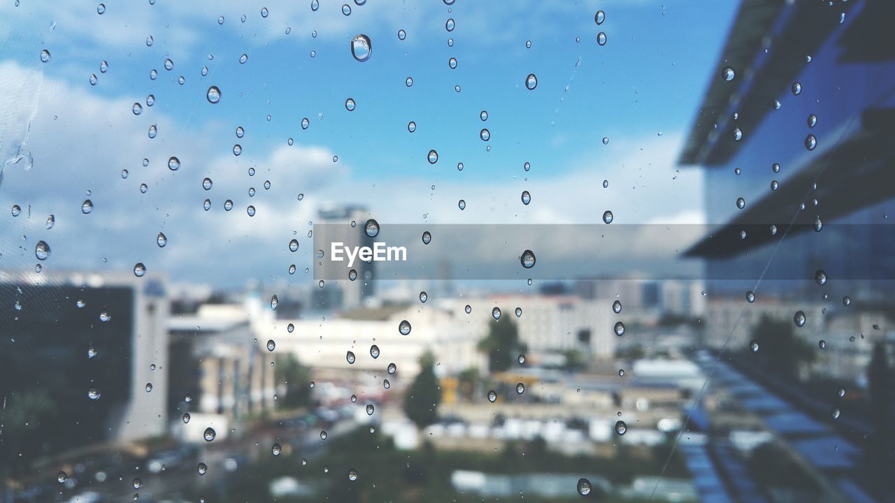 Water drops on glass against blurred buildings