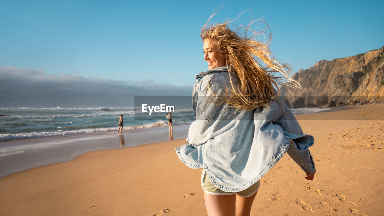 rear view of woman standing at beach against clear sky