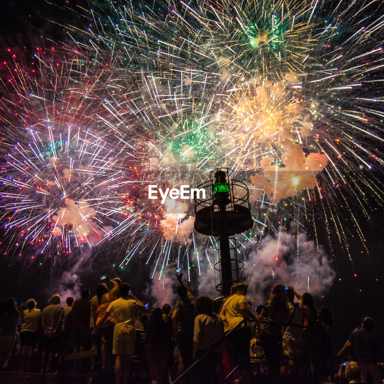 People looking at firework display at night