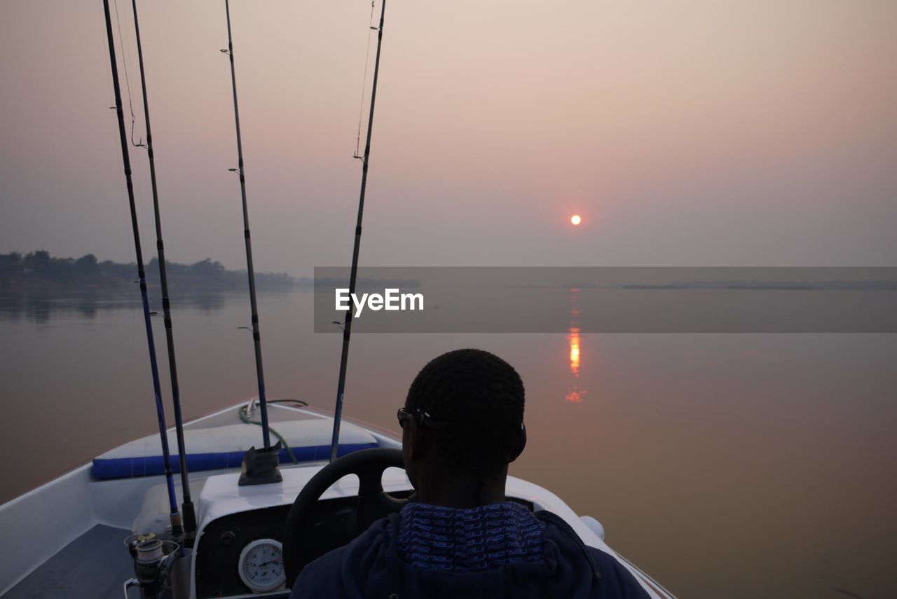 SILHOUETTE OF PERSON IN SEA DURING SUNSET