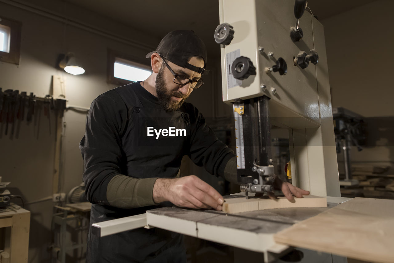 Woodworker working on band saw in workshop