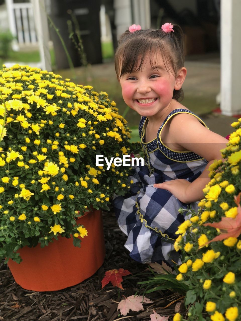 PORTRAIT OF SMILING GIRL WITH YELLOW FLOWERS IN PARK