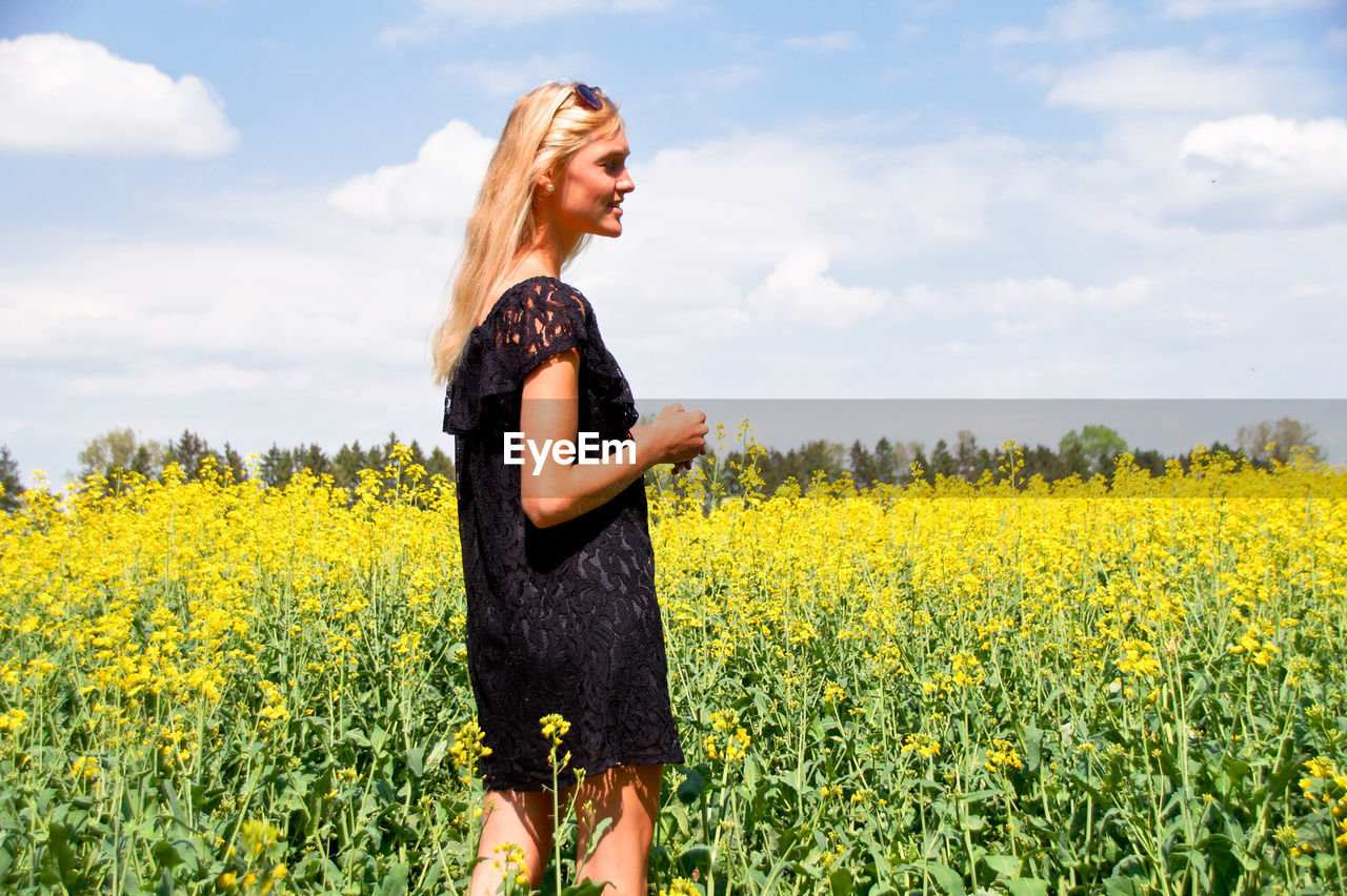 Woman standing on yellow flowering field