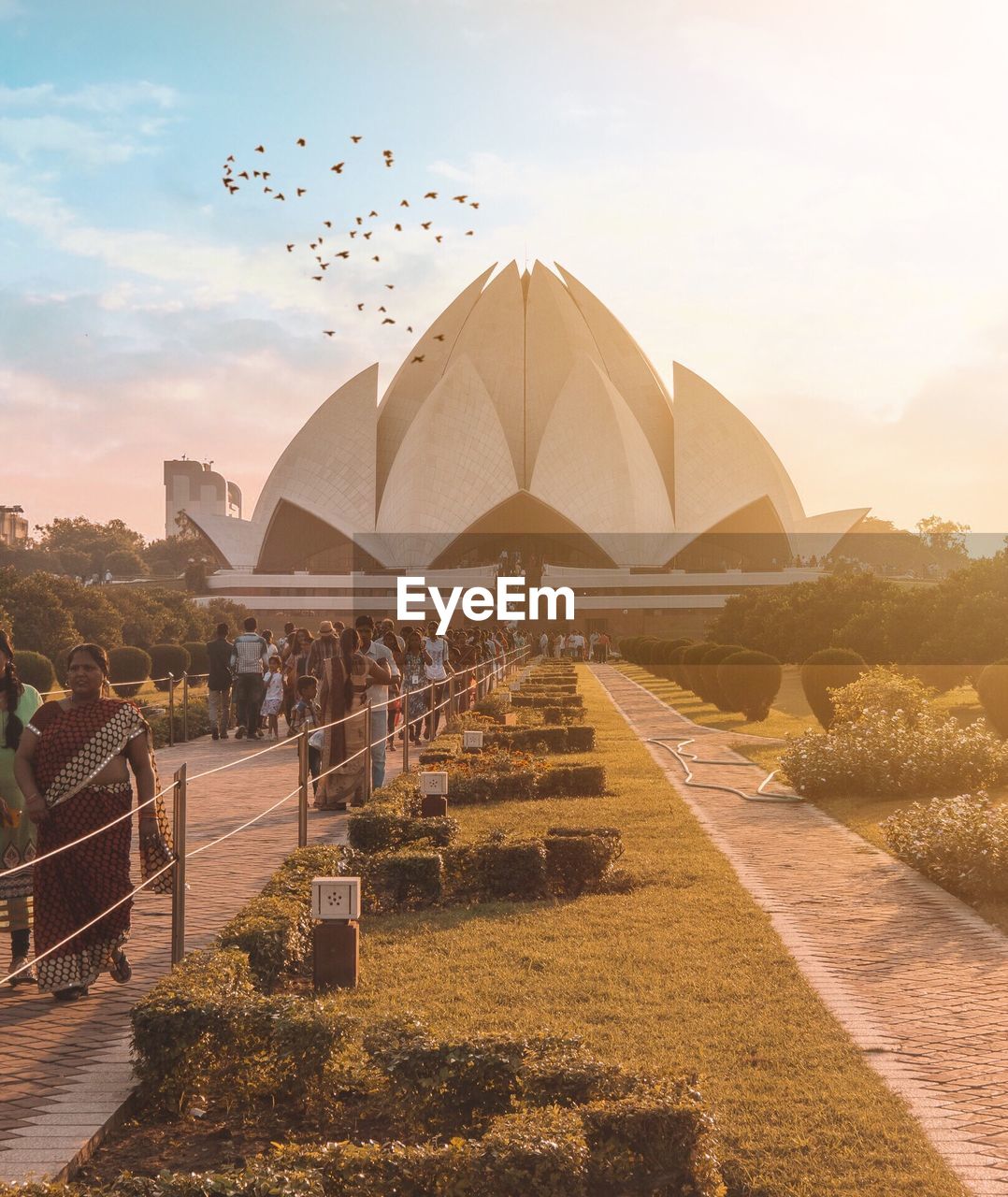 Tourists visiting lotus temple against sky during sunset