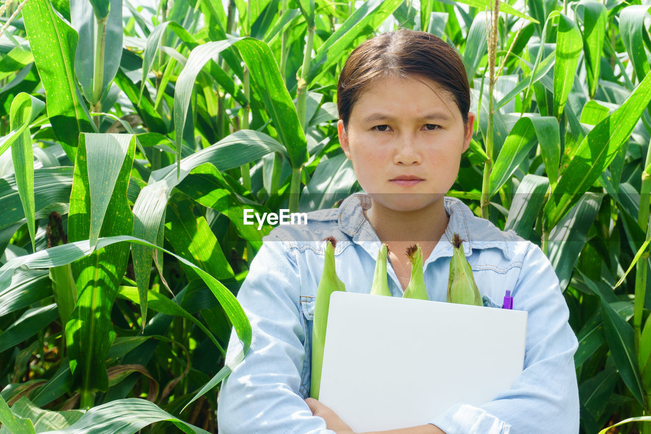 Young woman holding corn on field