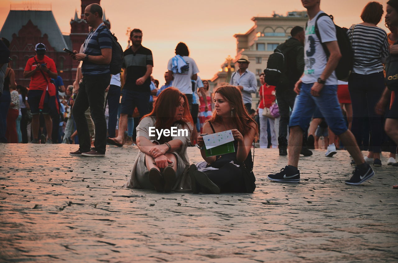 GROUP OF PEOPLE SITTING ON STREET IN CITY