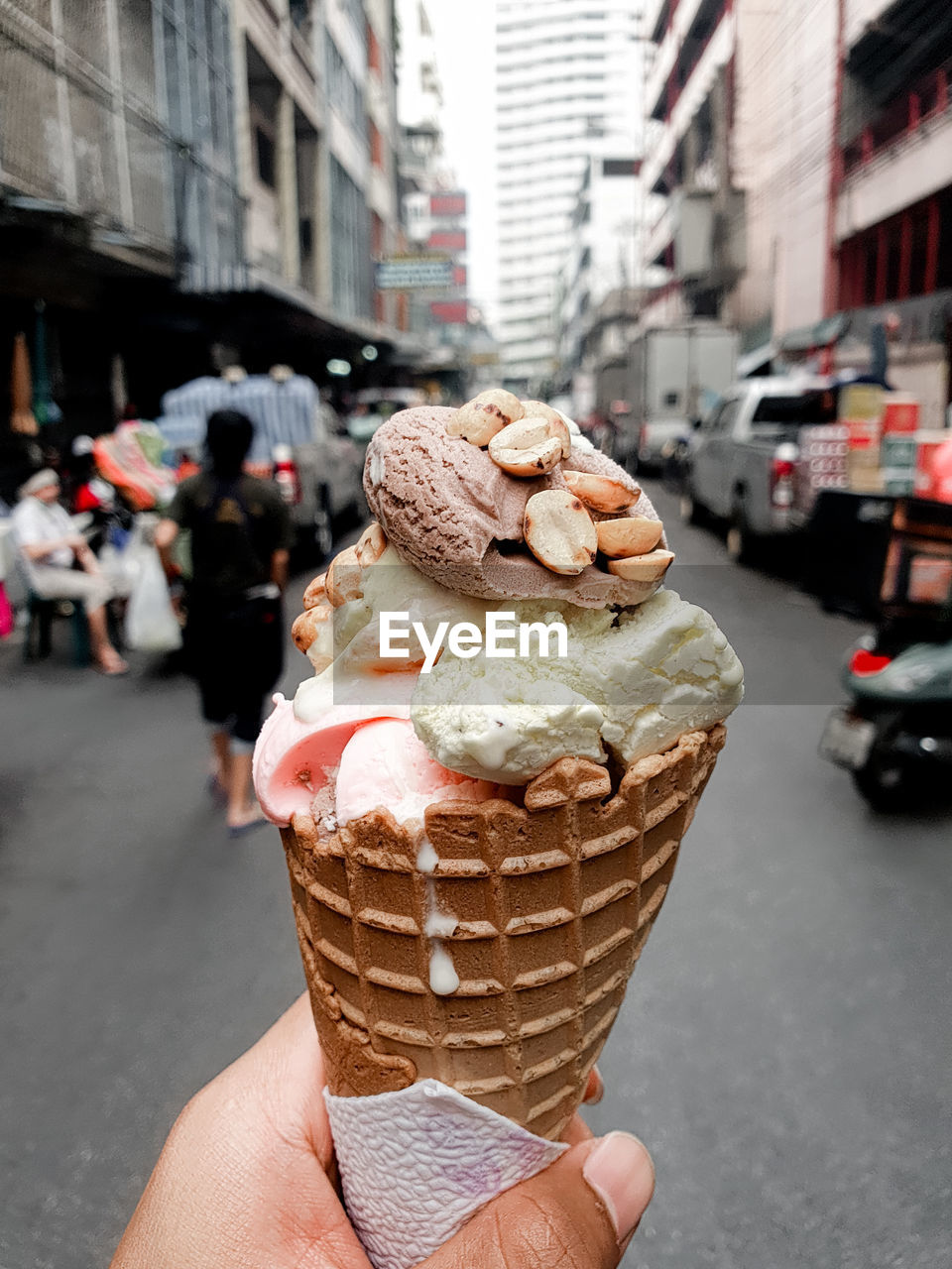 Hand holding ice cream cone on street