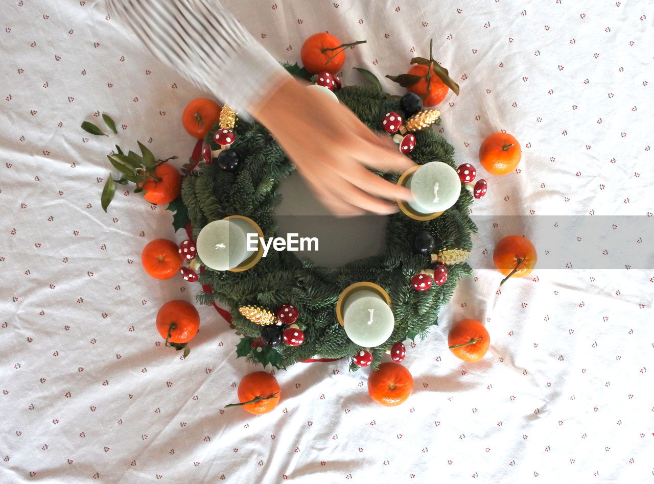 Cropped image of woman decorating christmas wreath on table