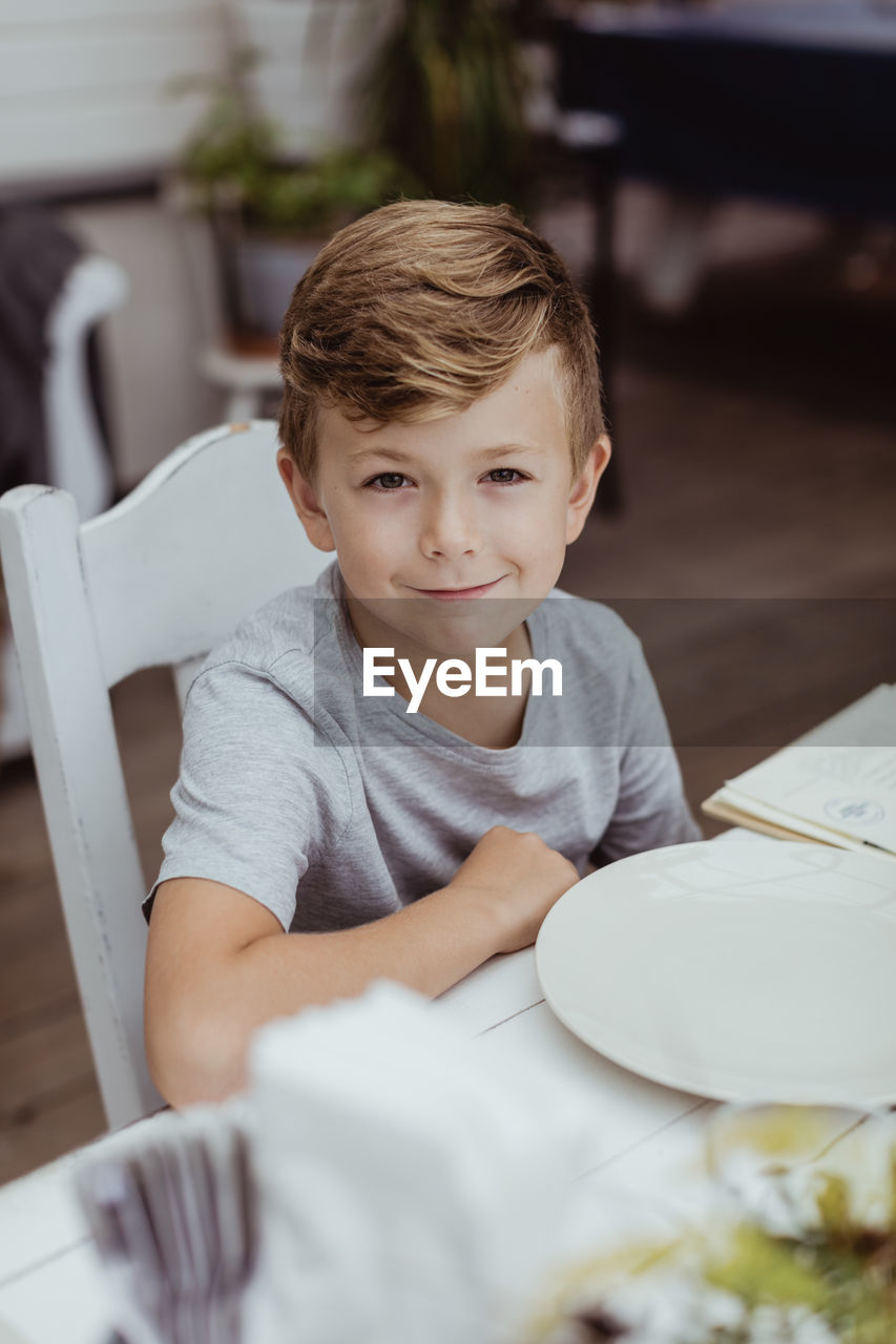 Portrait of smiling boy sitting at table in restaurant