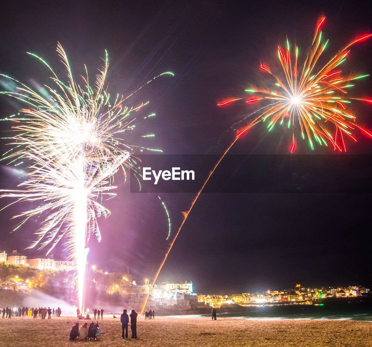 Firework display over sea against sky at night