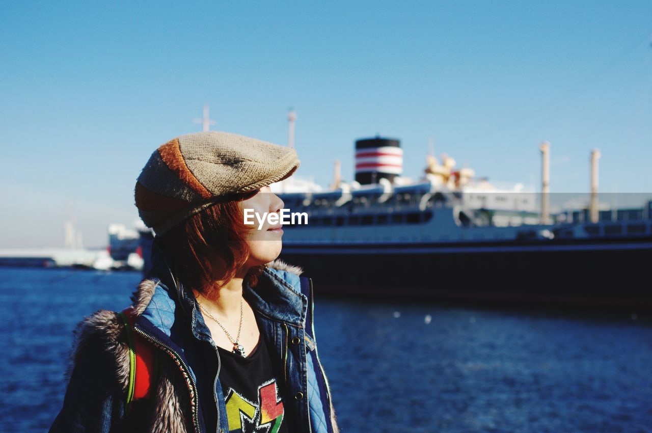 Woman wearing cap against sea in sunny day