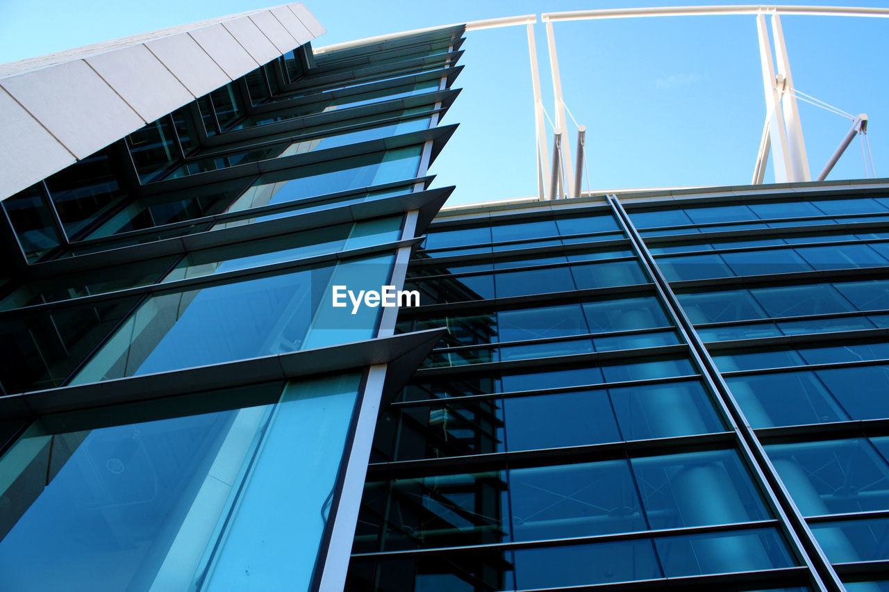 Low angle view of glass building against blue sky