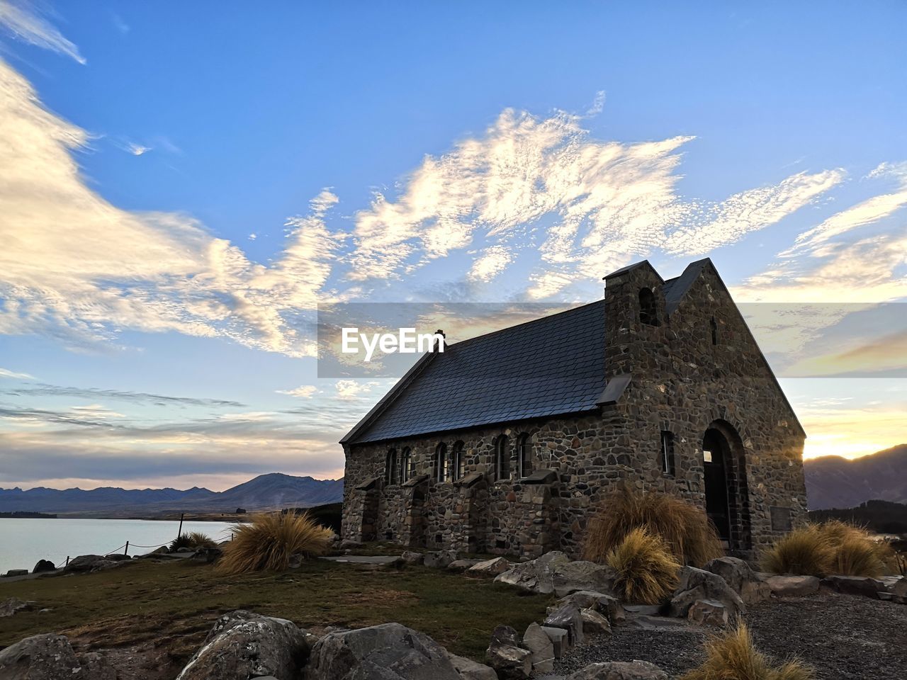 Historic small chapel by the lake against sky at sunrise
