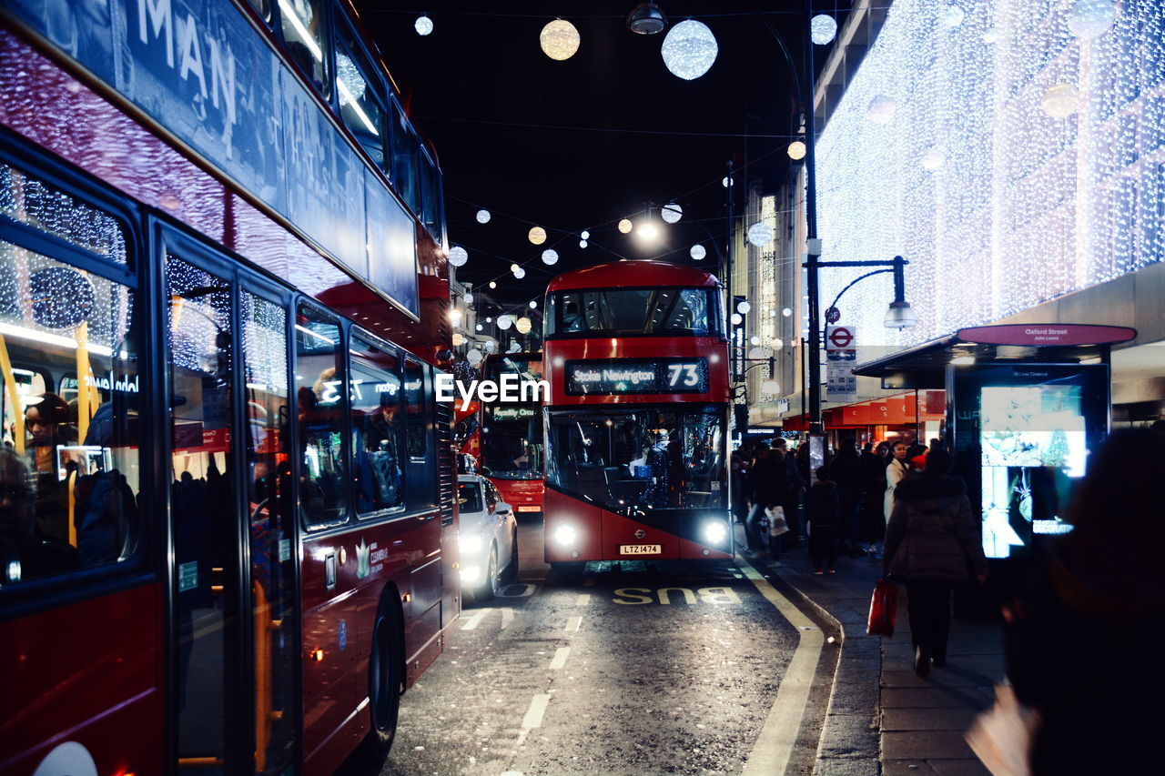 Illuminated double-decker busses on city street at night