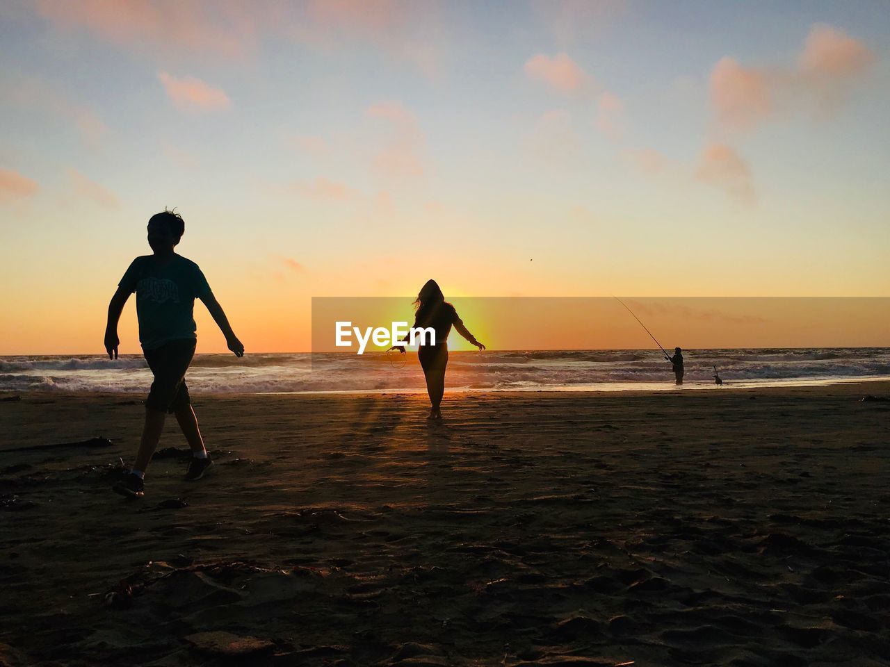 Silhouette people at beach against sky during sunset