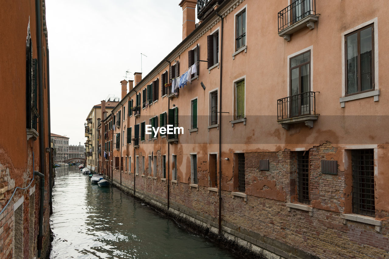 Canal amidst buildings in city against sky