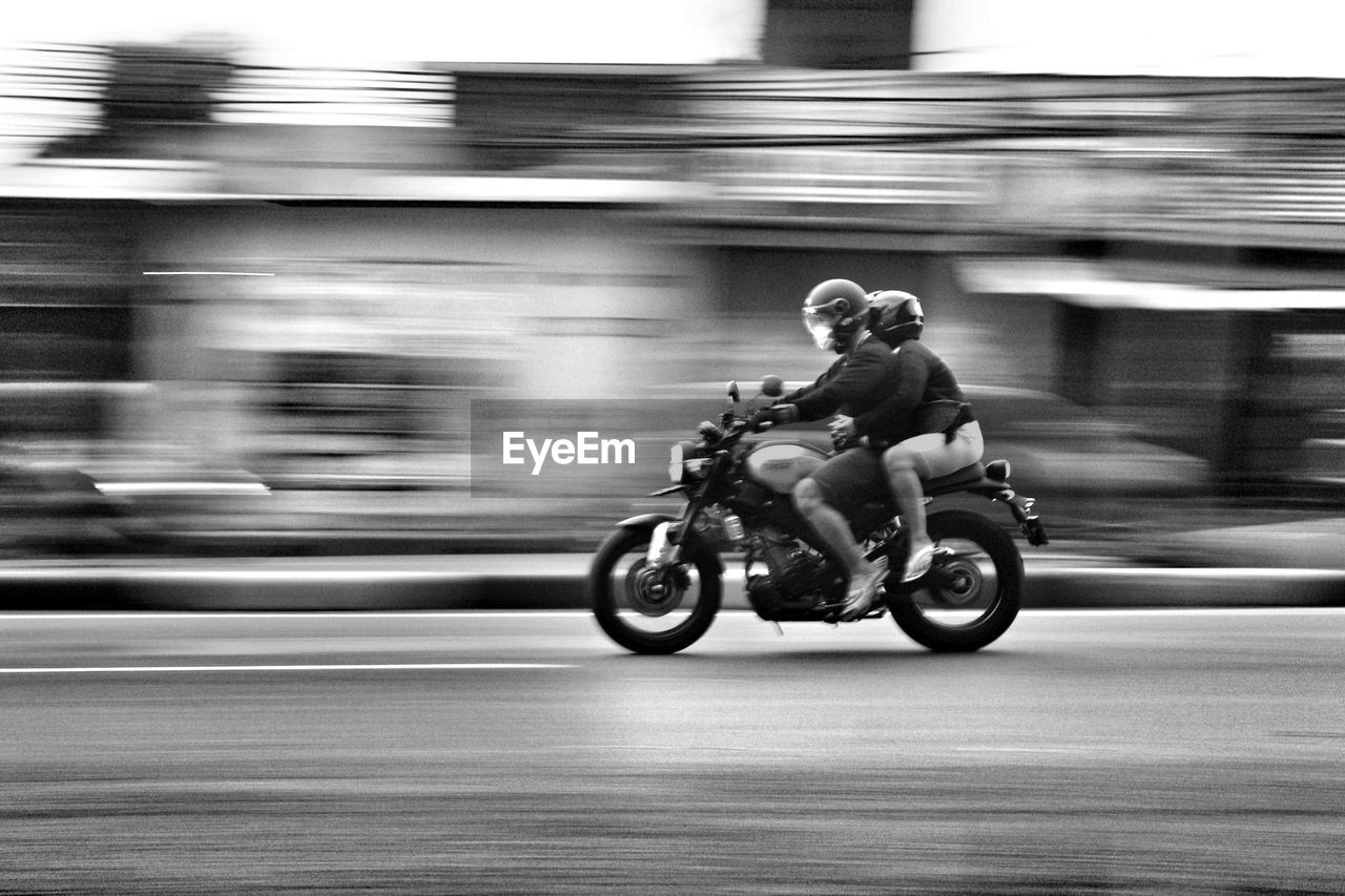 Blurred motion of man riding motorcycle on street