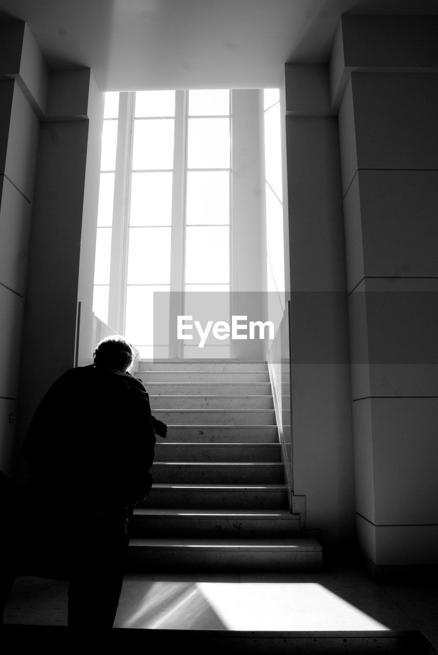 Rear view of man walking towards steps in building