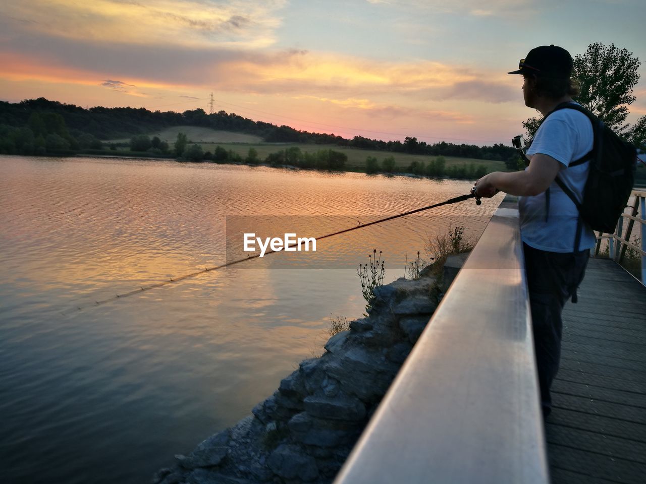 Side view of man fishing at lake during sunset