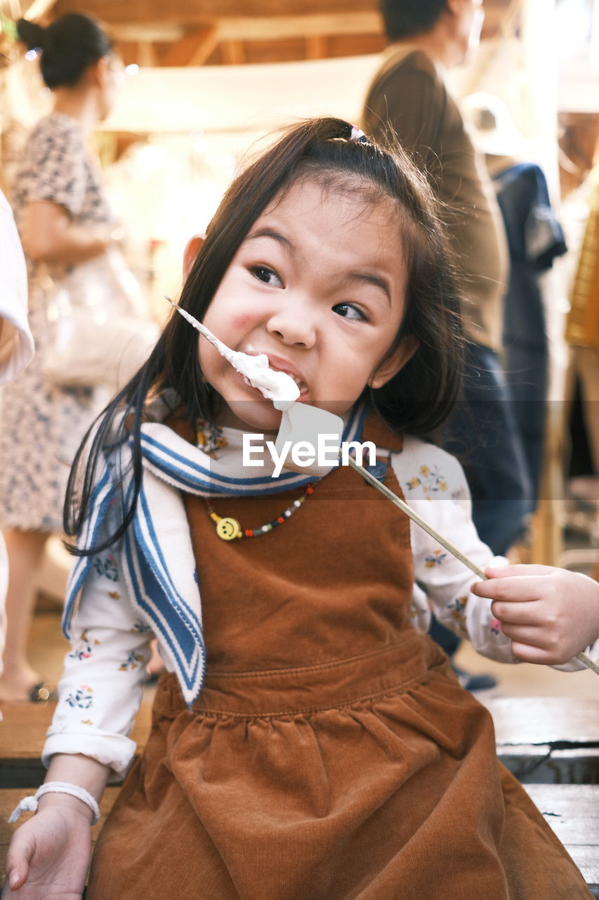 Cute childen eating marshmallow withe brown dress