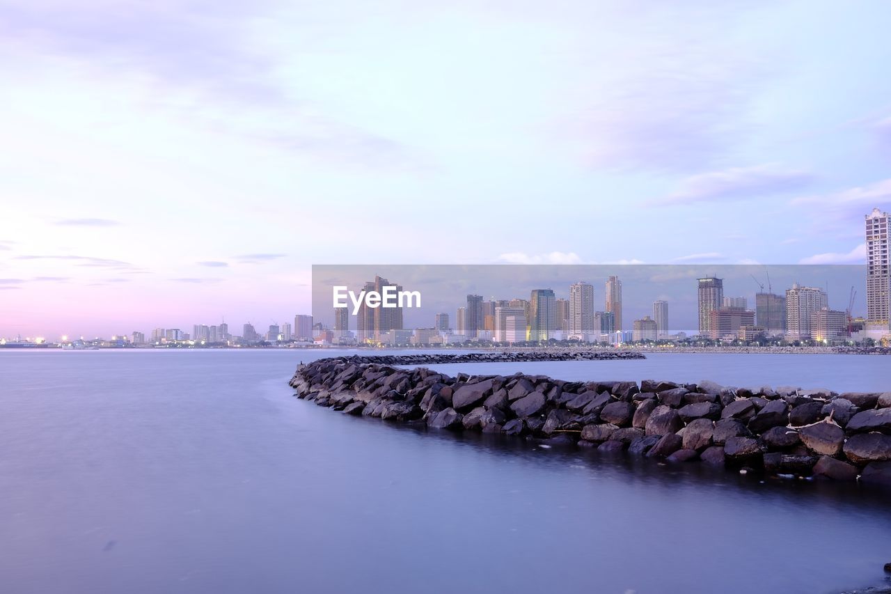 Rocks amidst sea against building against sky