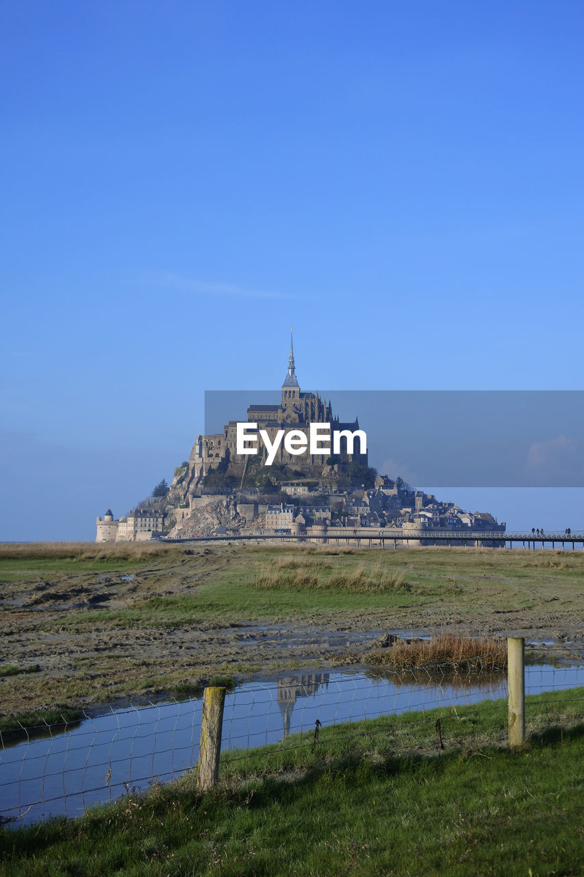 Mont saint michel against blue sky, reflection in the water normandy