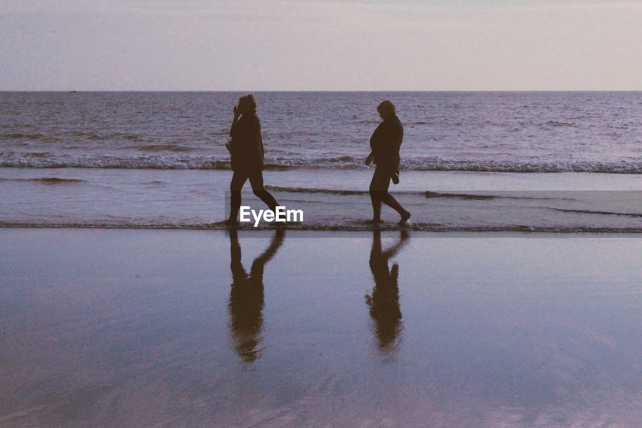 People walking on beach at dusk