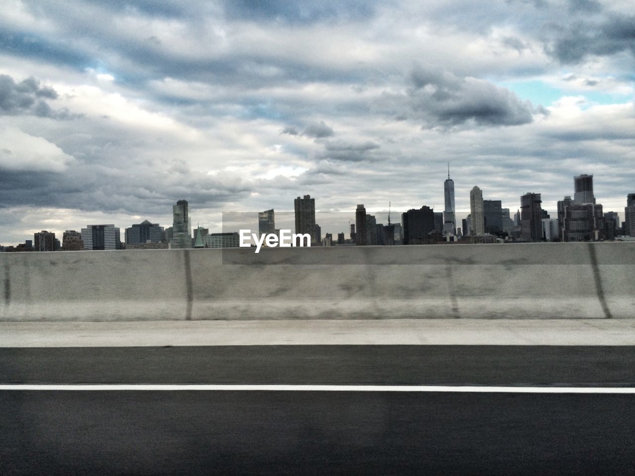 Road and buildings against cloudy sky