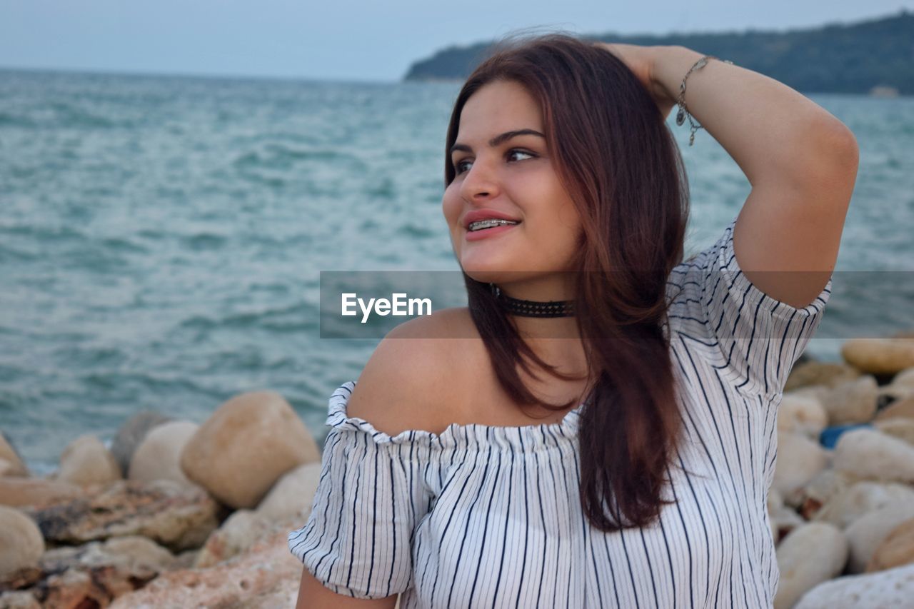 Young woman with long hair against sea