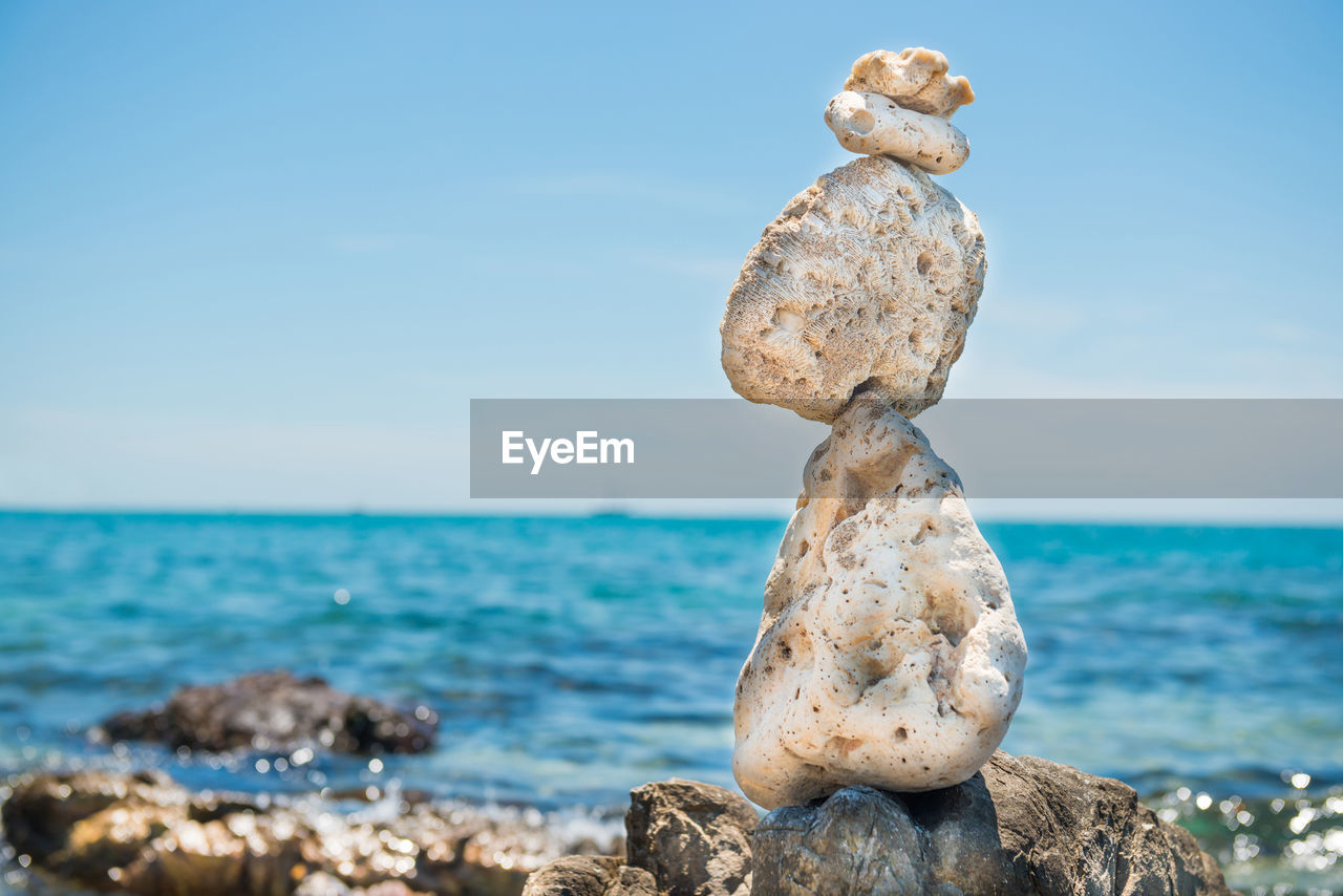 Zen stones balance at stony beach and sea background