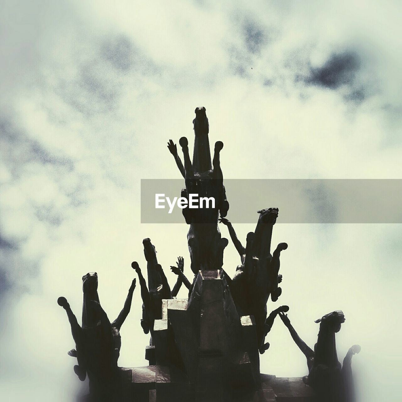 LOW ANGLE VIEW OF TWO PEOPLE AGAINST CLOUDY SKY