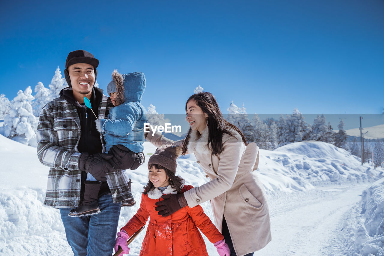 portrait of smiling female friends standing against snowcapped mountains