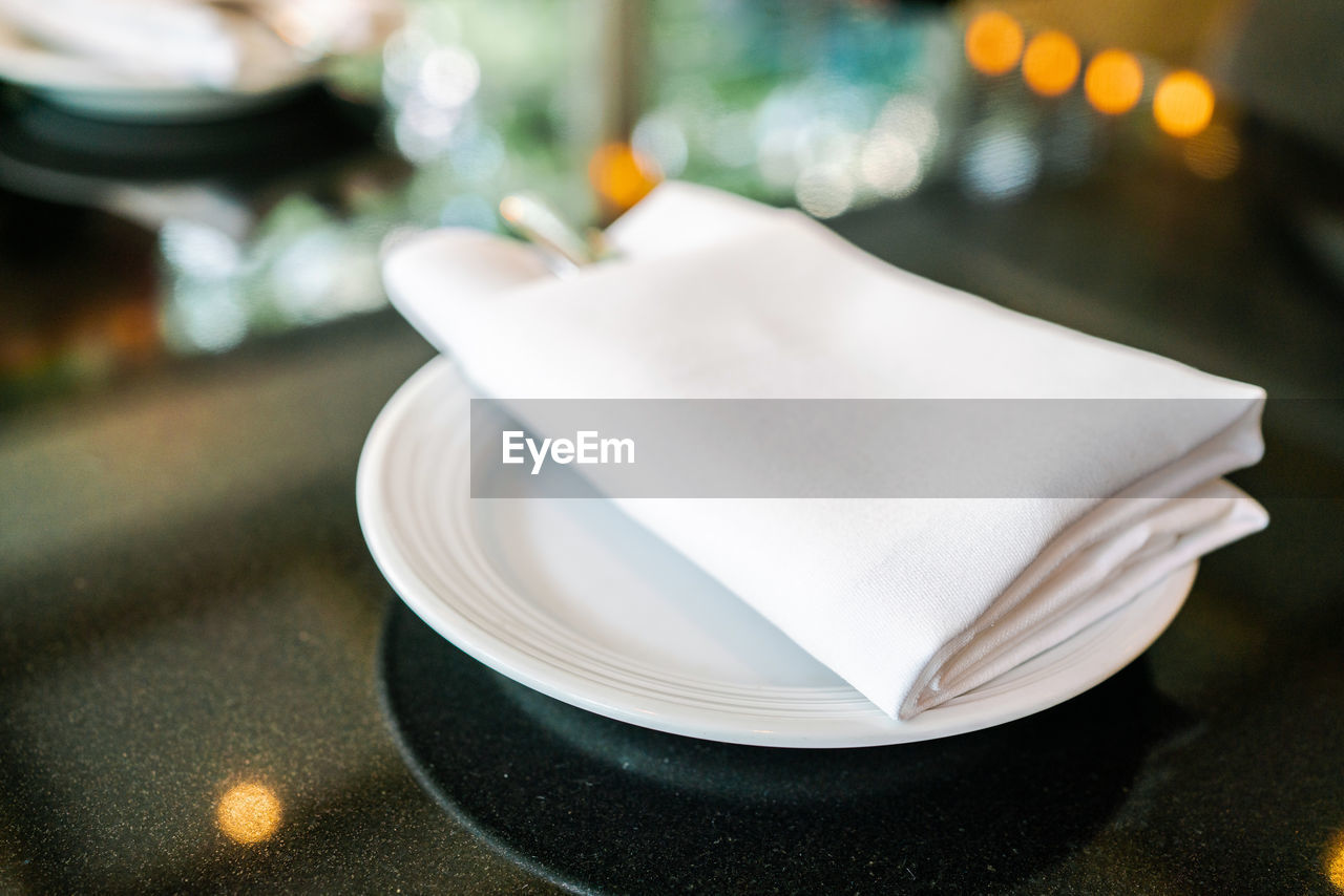 English afternoon tea table with white napkin, cutlery and plate on the black granite tabletop.