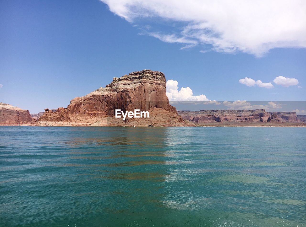 ROCK FORMATION IN WATER AGAINST BLUE SKY