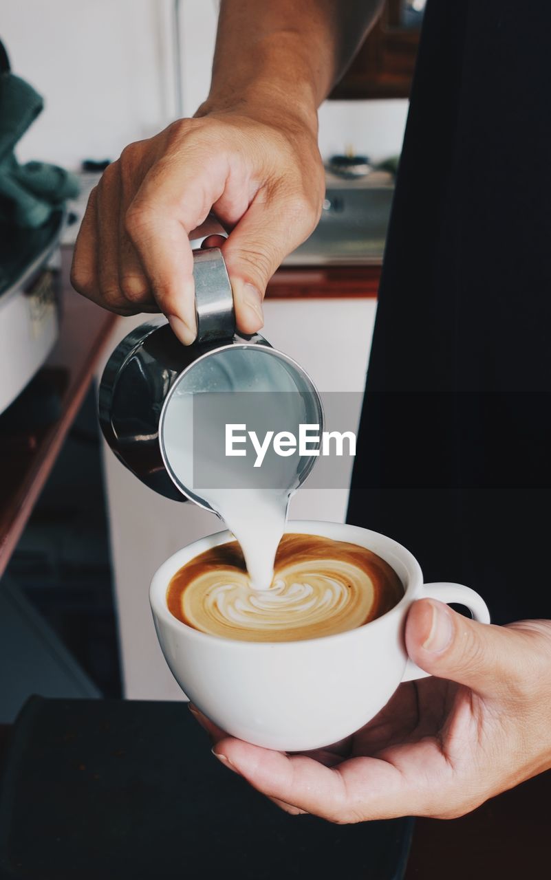 Cropped hand of man pouring coffee in glass