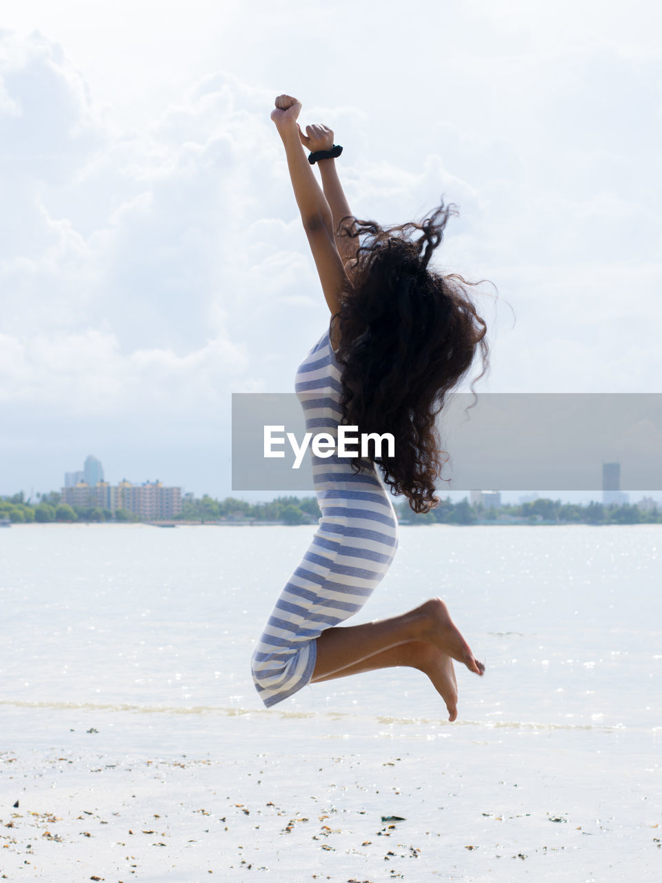 Woman jumping at beach against sky