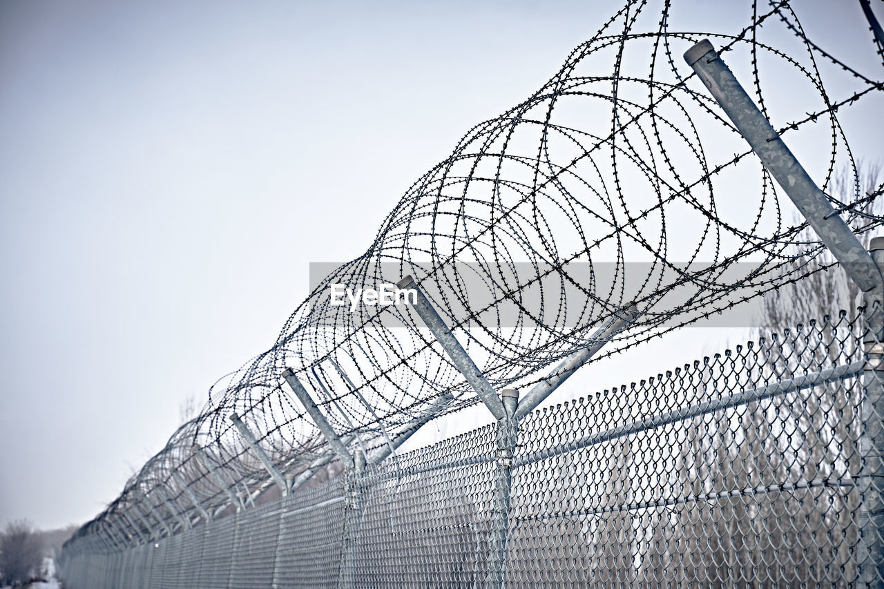 LOW ANGLE VIEW OF BARBED WIRE FENCE