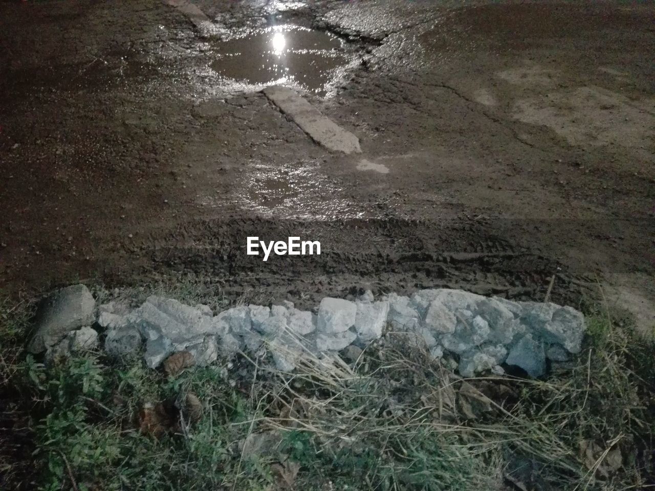 HIGH ANGLE VIEW OF ROCKS ON WET FIELD