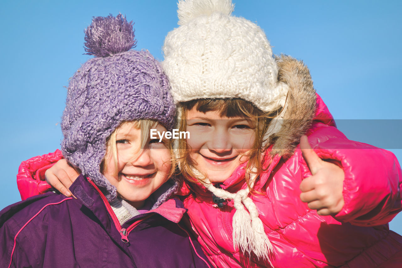 Close-up portrait of happy girls against sky