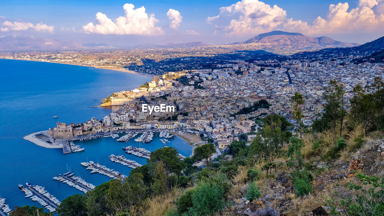 High angle view of city by sea against sky