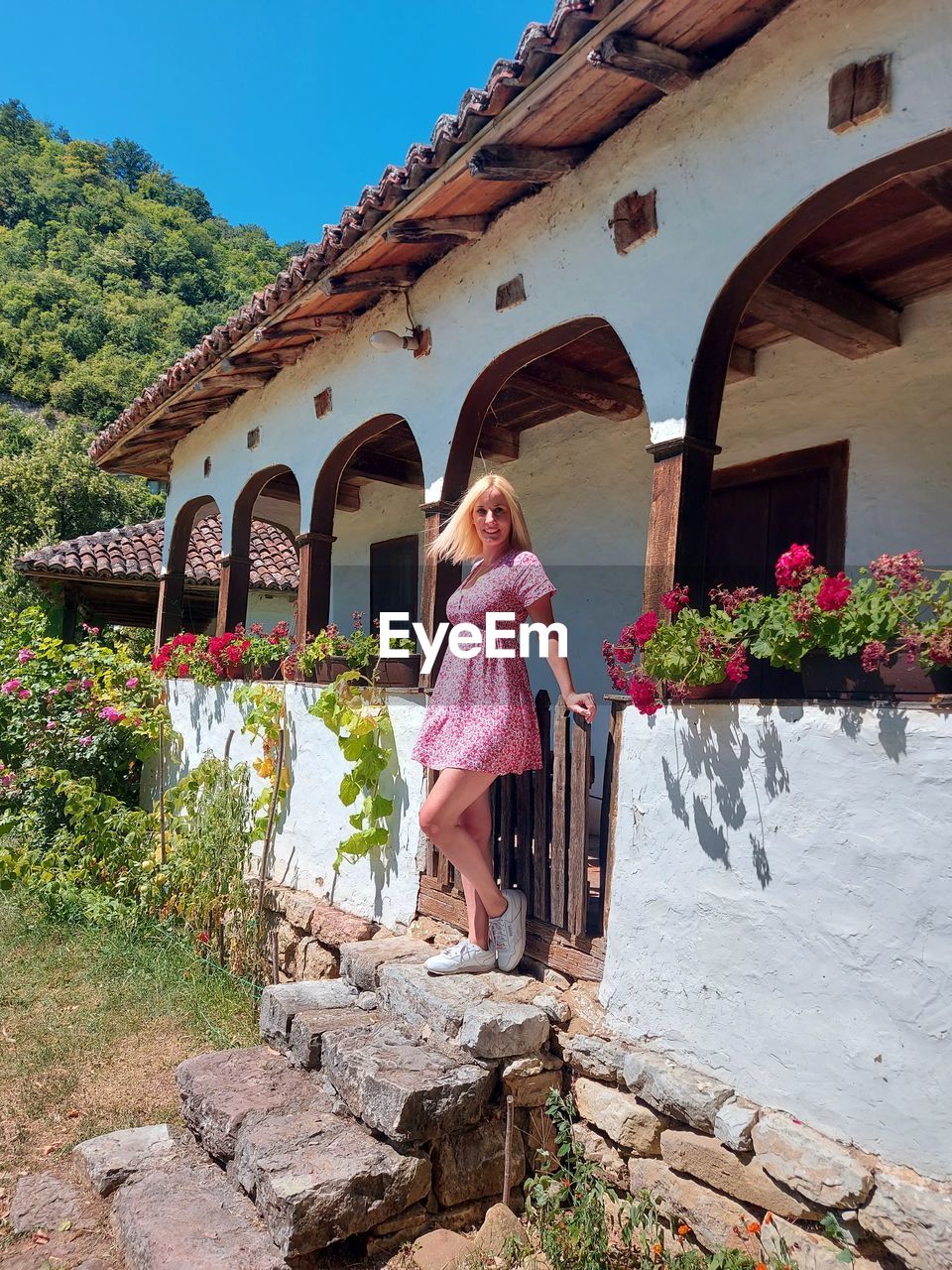 A young woman stands in front of the country house